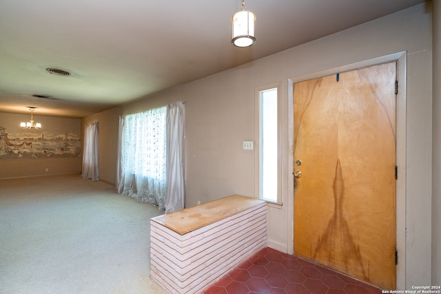 carpeted foyer entrance with an inviting chandelier