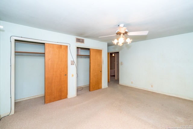 unfurnished bedroom with light carpet, ceiling fan, and multiple closets