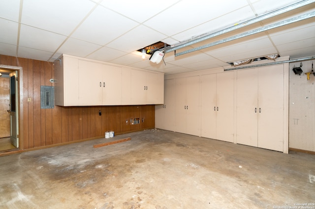 garage with a garage door opener, wooden walls, and electric panel