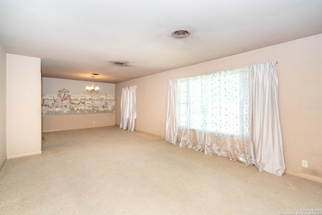 spare room with light carpet and a chandelier