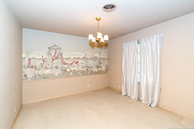 carpeted spare room featuring an inviting chandelier