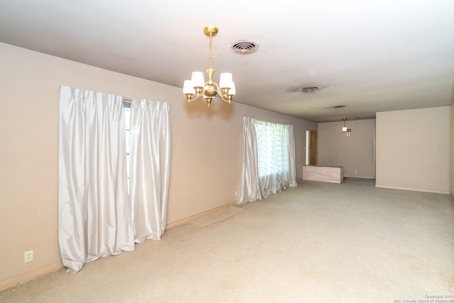 carpeted empty room featuring an inviting chandelier