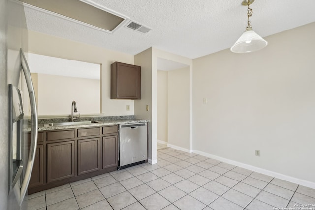 kitchen featuring dark brown cabinetry, light tile patterned floors, sink, decorative light fixtures, and stainless steel appliances