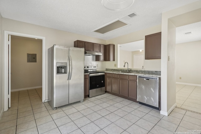 kitchen featuring light tile patterned floors, a textured ceiling, stainless steel appliances, and sink