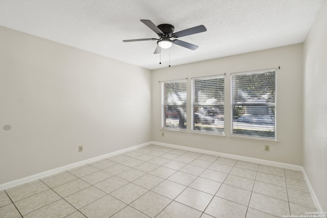 empty room with ceiling fan, a textured ceiling, and light tile patterned floors