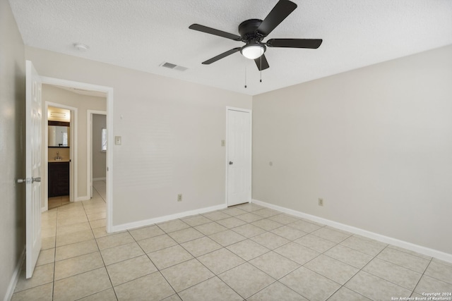 spare room featuring ceiling fan, light tile patterned floors, and a textured ceiling