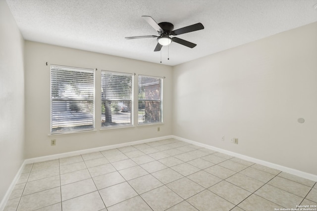 spare room featuring a textured ceiling, light tile patterned flooring, and ceiling fan