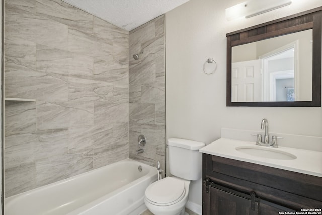 full bathroom with a textured ceiling, vanity, toilet, and tiled shower / bath