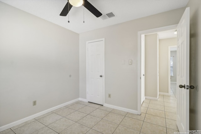 unfurnished bedroom with light tile patterned floors, ceiling fan, and a closet