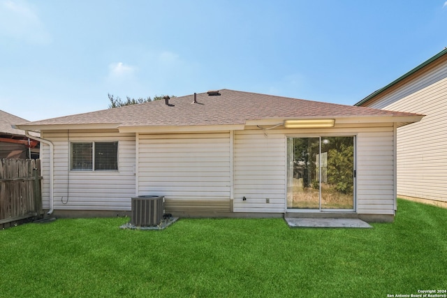 rear view of property featuring a lawn and central air condition unit