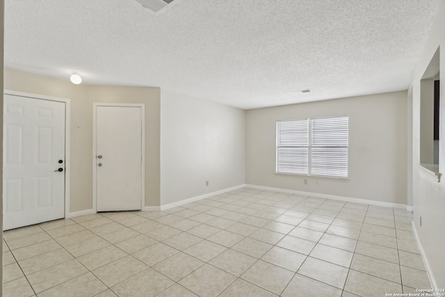 spare room with a textured ceiling and light tile patterned flooring