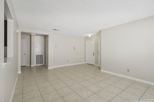 tiled empty room with a textured ceiling