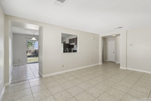 tiled empty room with a textured ceiling