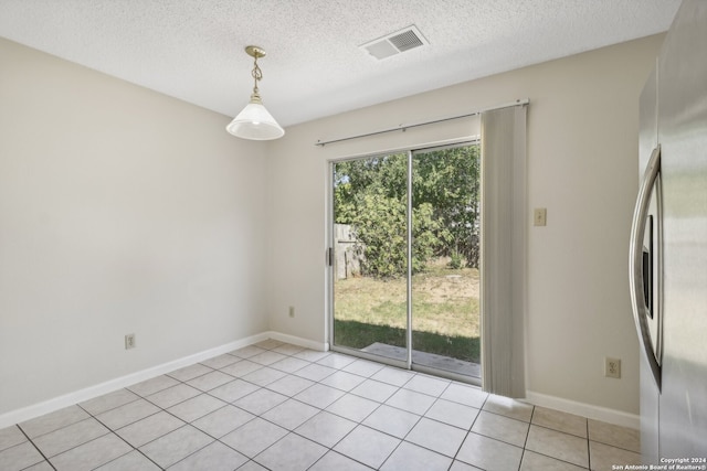 unfurnished dining area featuring a textured ceiling and light tile patterned floors