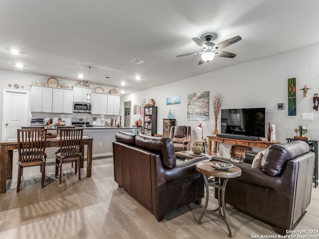 living room with ceiling fan and light hardwood / wood-style flooring