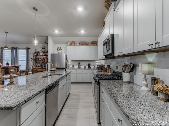 kitchen featuring pendant lighting, sink, white cabinets, appliances with stainless steel finishes, and a spacious island