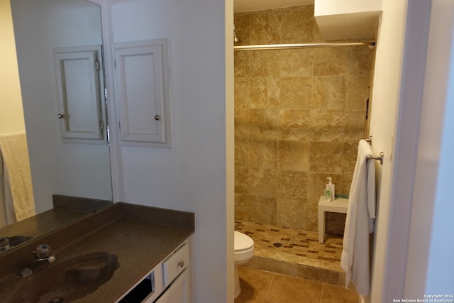 bathroom featuring tiled shower, vanity, toilet, and tile patterned flooring