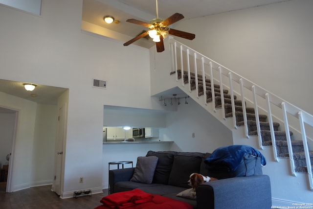 living room featuring wood-type flooring, a towering ceiling, and ceiling fan