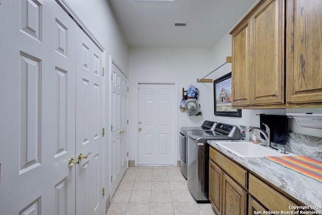 laundry area with cabinets, washer and dryer, light tile patterned floors, and sink