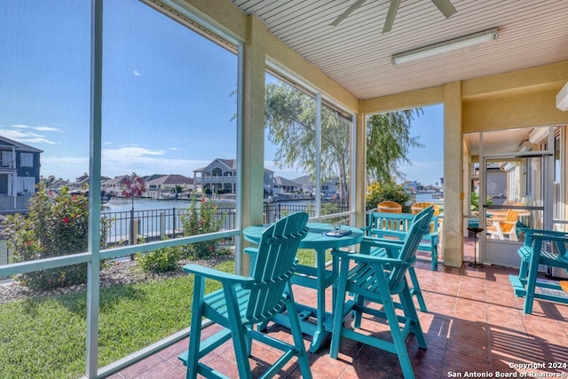 sunroom / solarium with a water view and ceiling fan