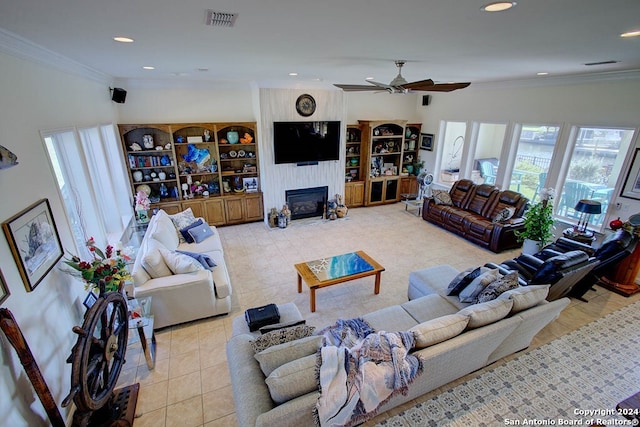 living room featuring a fireplace, ornamental molding, ceiling fan, and light tile patterned flooring