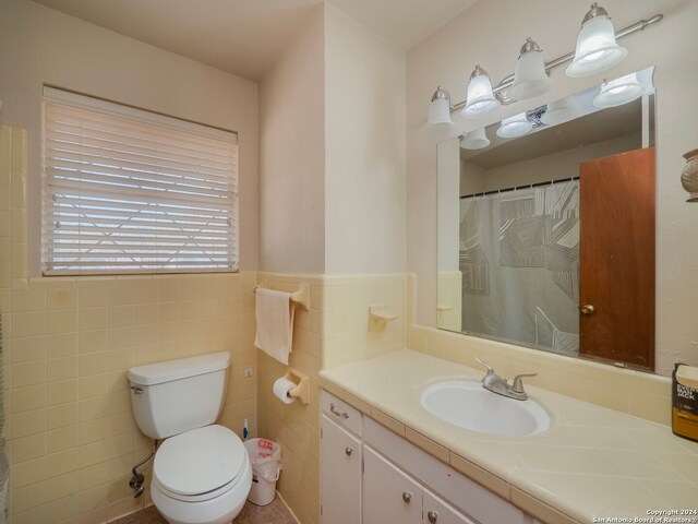 bathroom with tile walls, vanity, and toilet