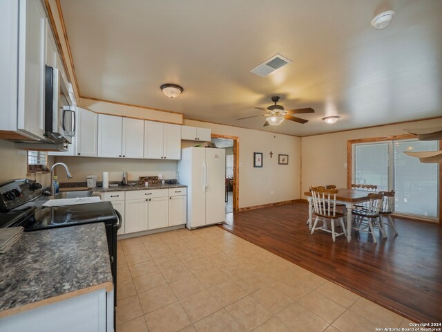 kitchen with black range with electric stovetop, white cabinets, white fridge, light wood-type flooring, and ceiling fan