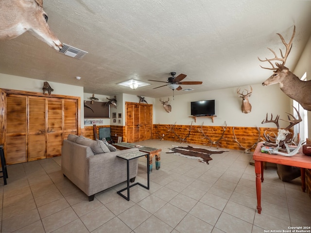 living room featuring ceiling fan, light tile patterned flooring, and a textured ceiling