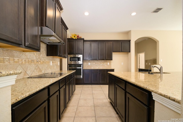 kitchen featuring light stone counters, light tile patterned floors, range hood, and appliances with stainless steel finishes