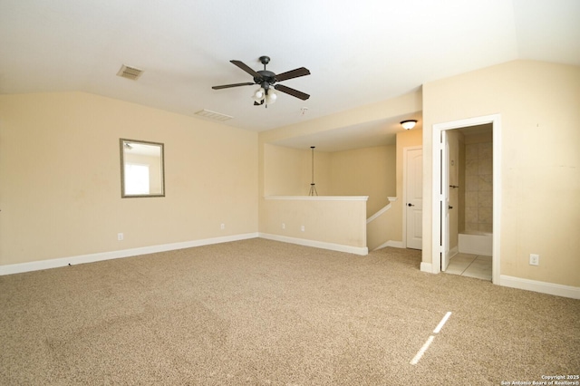 spare room featuring ceiling fan, light colored carpet, and vaulted ceiling