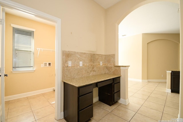 kitchen with light stone countertops, light tile patterned floors, and dark brown cabinets