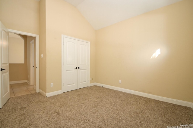 unfurnished bedroom featuring carpet flooring, a closet, and vaulted ceiling