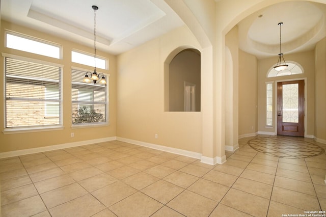 foyer featuring light tile patterned floors, a tray ceiling, and a notable chandelier