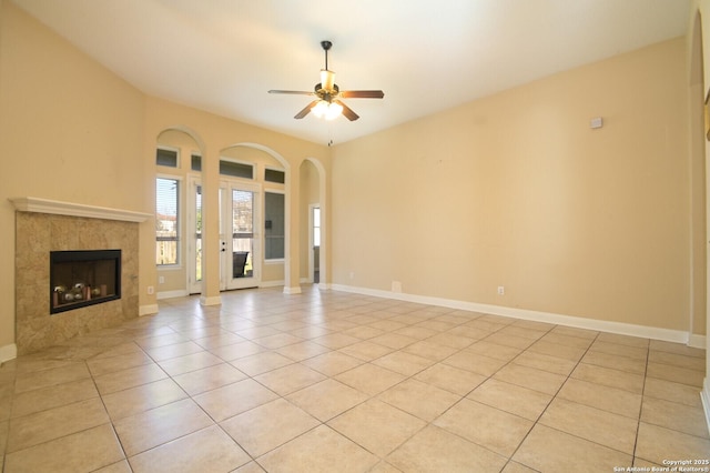 unfurnished living room featuring ceiling fan, a fireplace, and light tile patterned floors