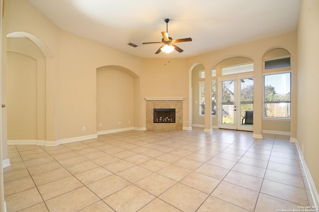 unfurnished living room featuring a fireplace, light tile patterned floors, and ceiling fan