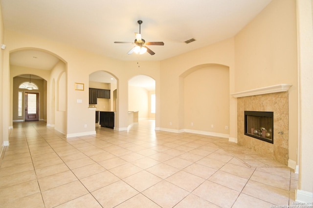 unfurnished living room with ceiling fan, light tile patterned flooring, and a fireplace