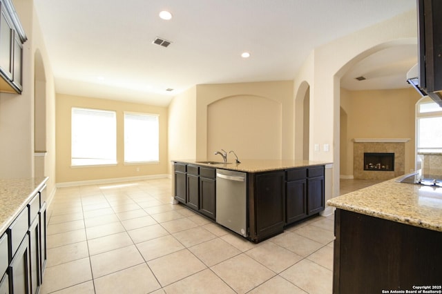 kitchen with light stone countertops, dishwasher, light tile patterned floors, and sink