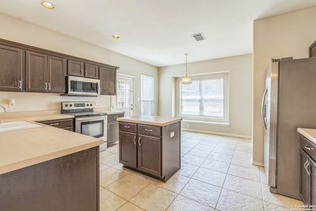 kitchen featuring stainless steel appliances, plenty of natural light, a kitchen island, and sink