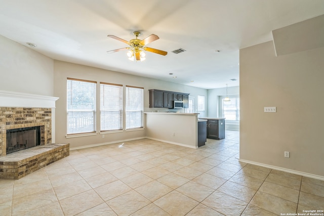 unfurnished living room featuring ceiling fan, a fireplace, and light tile patterned floors