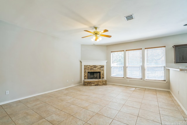 unfurnished living room with light tile patterned flooring, ceiling fan, and a brick fireplace