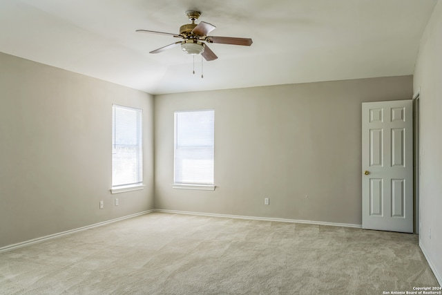 empty room with lofted ceiling, ceiling fan, and light colored carpet