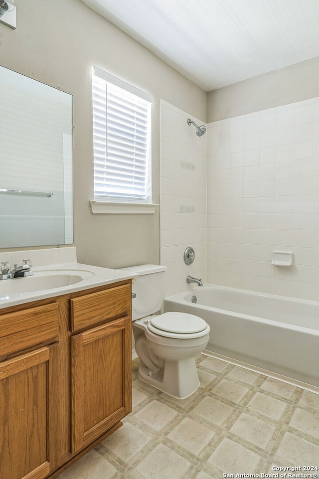 full bathroom featuring tiled shower / bath, vanity, and toilet