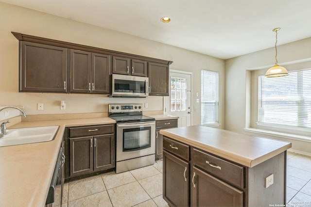 kitchen with appliances with stainless steel finishes, hanging light fixtures, light tile patterned floors, dark brown cabinetry, and sink