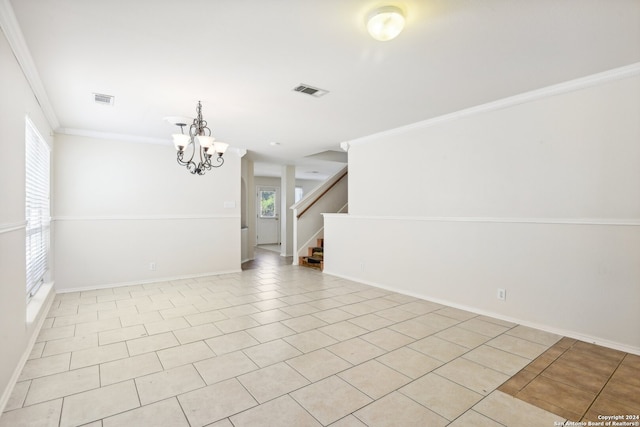 spare room featuring ornamental molding, light tile patterned flooring, and an inviting chandelier