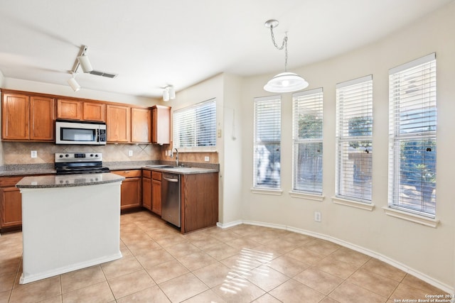 kitchen with appliances with stainless steel finishes, backsplash, pendant lighting, and a wealth of natural light