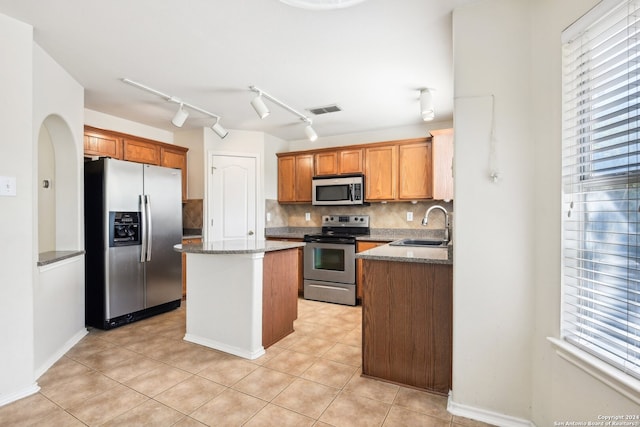 kitchen featuring appliances with stainless steel finishes, decorative backsplash, light tile patterned flooring, a center island, and sink