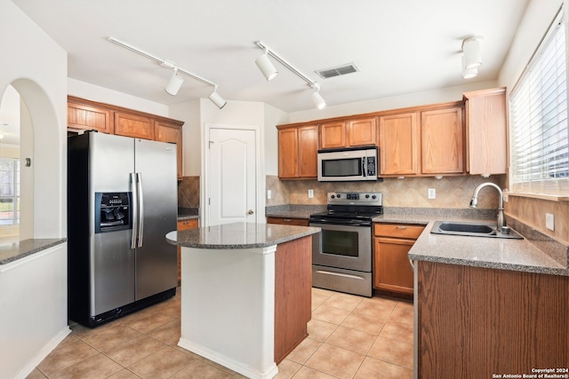 kitchen featuring light tile patterned floors, sink, a kitchen island, appliances with stainless steel finishes, and decorative backsplash