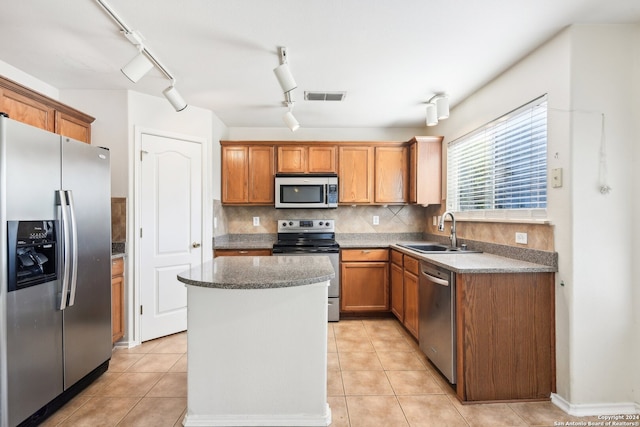 kitchen featuring light tile patterned flooring, stainless steel appliances, sink, and a center island