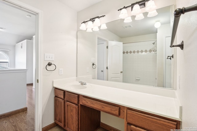 bathroom with a tile shower, vanity, and hardwood / wood-style flooring