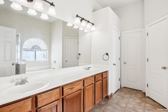 bathroom with a tub to relax in, vanity, and tile patterned floors